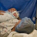 New mom holding baby in OR after gentle cesarean birth