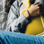 Holding a Hot Water Bottle on her abdomen, Childbirth Afterpains