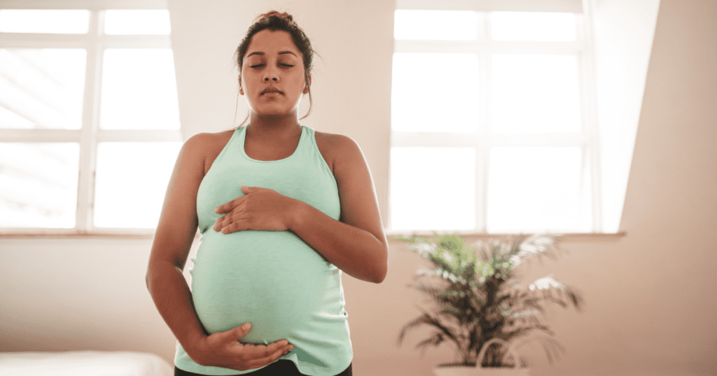 pregnant woman, holds belly with eyes closed, preparing for a vbac