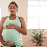 pregnant woman, holds belly with eyes closed, preparing for a vbac