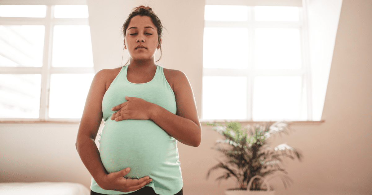 pregnant woman, holds belly with eyes closed, preparing for a vbac