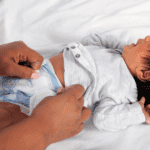 A mom changing newborn poop diaper