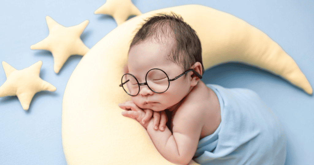 Newborn sleeping on a moon pillow with star pillows around him
