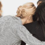 Woman embracing another women in a therapy group, recovering after a traumatic birth experience