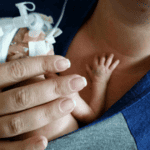 Tiny baby in the NICU resting on Mom