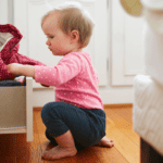 childproofing checklist, baby playing in a drawer in the bedroom