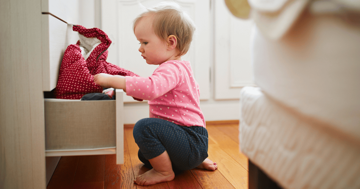 childproofing checklist, baby playing in a drawer in the bedroom