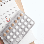 Postpartum Birth Control Guide, pills on top of a calendar with a pencil