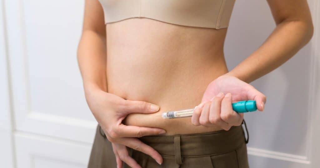 Lady making an injection into her belly, hormone imbalance after IVF