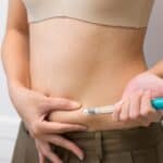 Lady making an injection into her belly, hormone imbalance after IVF