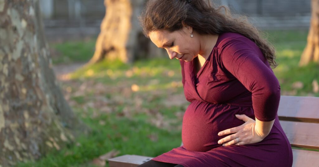 Pregnant woman outside leaning over, unusual pregnancy symptoms