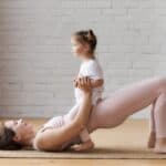 Mom with her daughter on her lap, doing a glute bridge, diastases recti