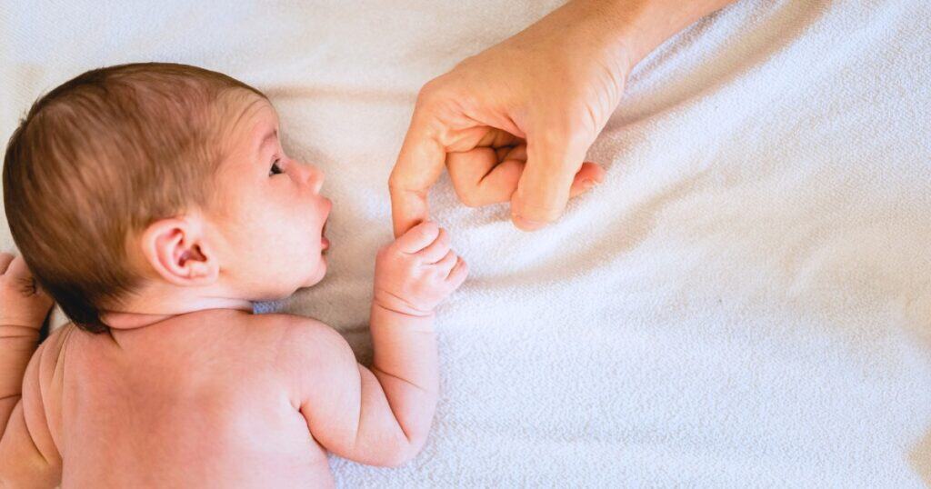 the first six weeks postpartum, newborn baby holds parents finger