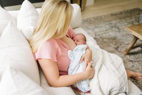 new mom breastfeeding on couch at home