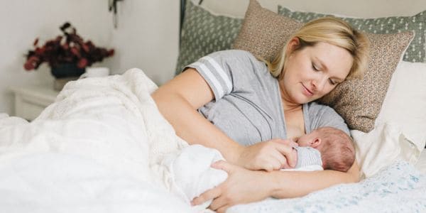 new mom breastfeeding in bed at home