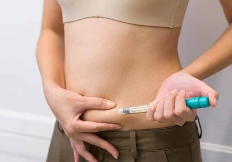Lady making an injection into her belly, hormone imbalance after IVF