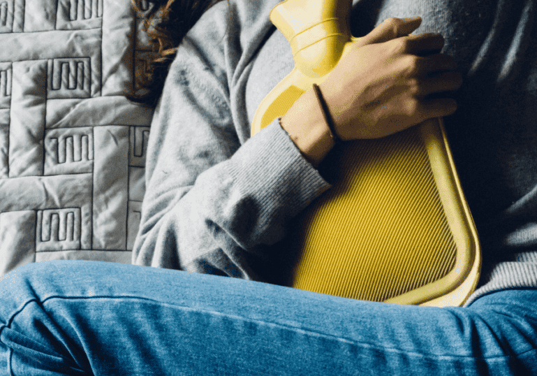 Holding a Hot Water Bottle on her abdomen, Childbirth Afterpains
