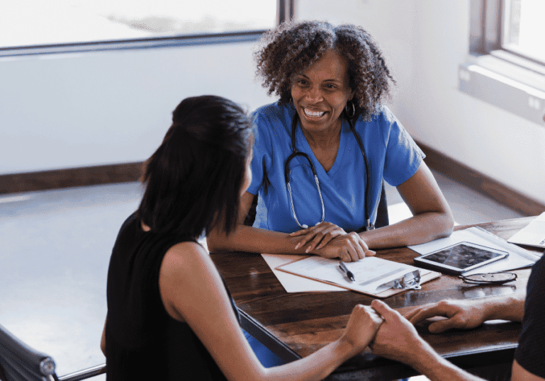 Choosing an OB/GYN or Midwife, a care provider sits with a family