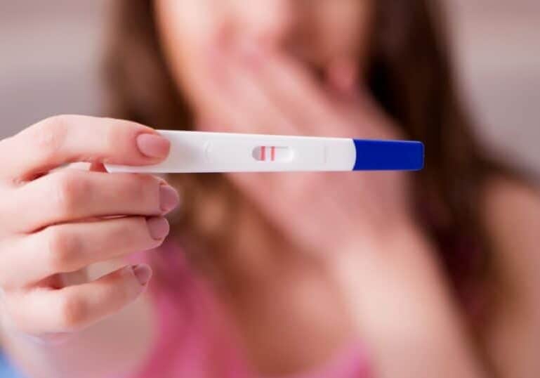 early pregnancy signs, lady holding up a pregnancy test