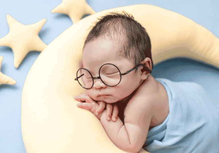 Newborn sleeping on a moon pillow with star pillows around him