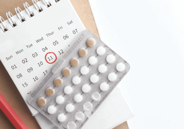 Postpartum Birth Control Guide, pills on top of a calendar with a pencil