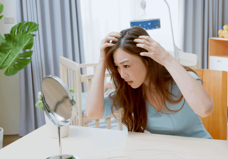 New mother looking at her postpartum hair loss in the mirror