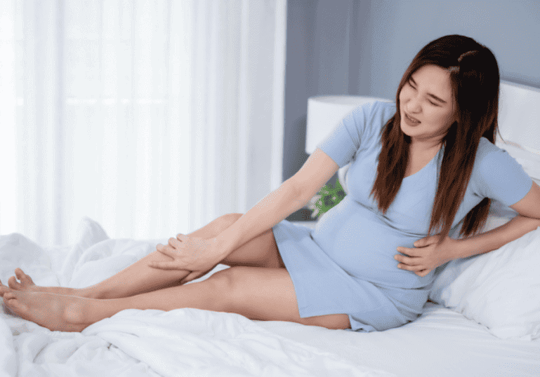 Pregnant women holding leg in pain, pregnancy ailments