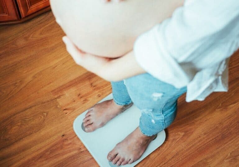 pregnant mom standing on a scale, pregnancy weight gain