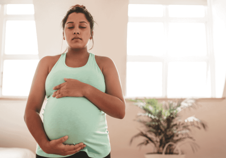 pregnant woman, holds belly with eyes closed, preparing for a vbac