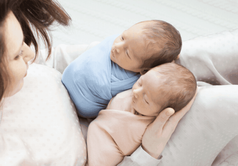 newborn twin babies with mother nursery setup
