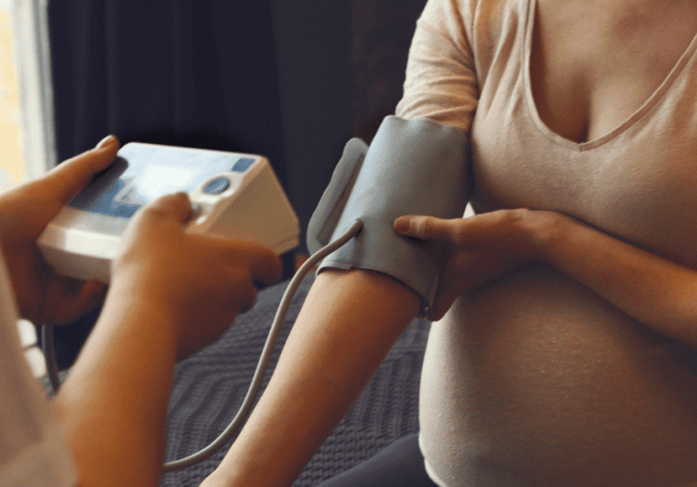 taking blood pressure of a pregnant mother, monitoring for preeclampsia