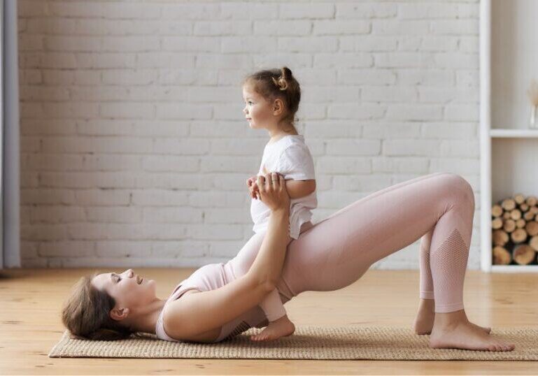 Mom with her daughter on her lap, doing a glute bridge, diastases recti
