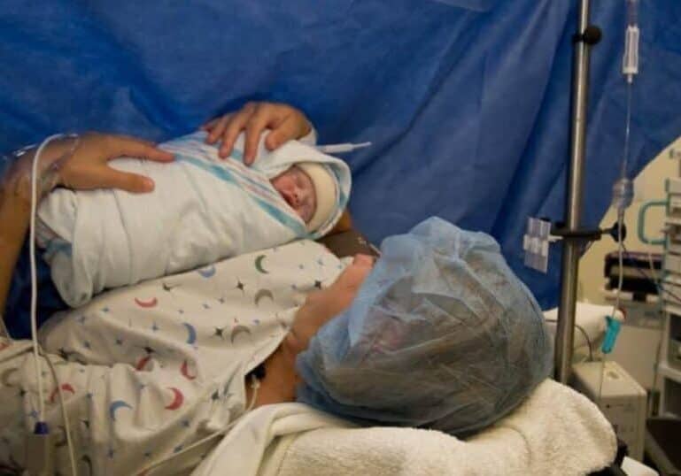 New mom holding baby in OR after gentle cesarean birth