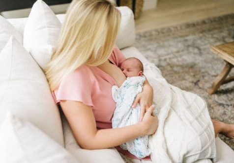 new mom breastfeeding on couch at home