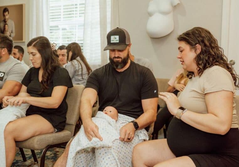 pregnant couple practice swaddling at Tampa newborn care class with Buddha Belly Doulas